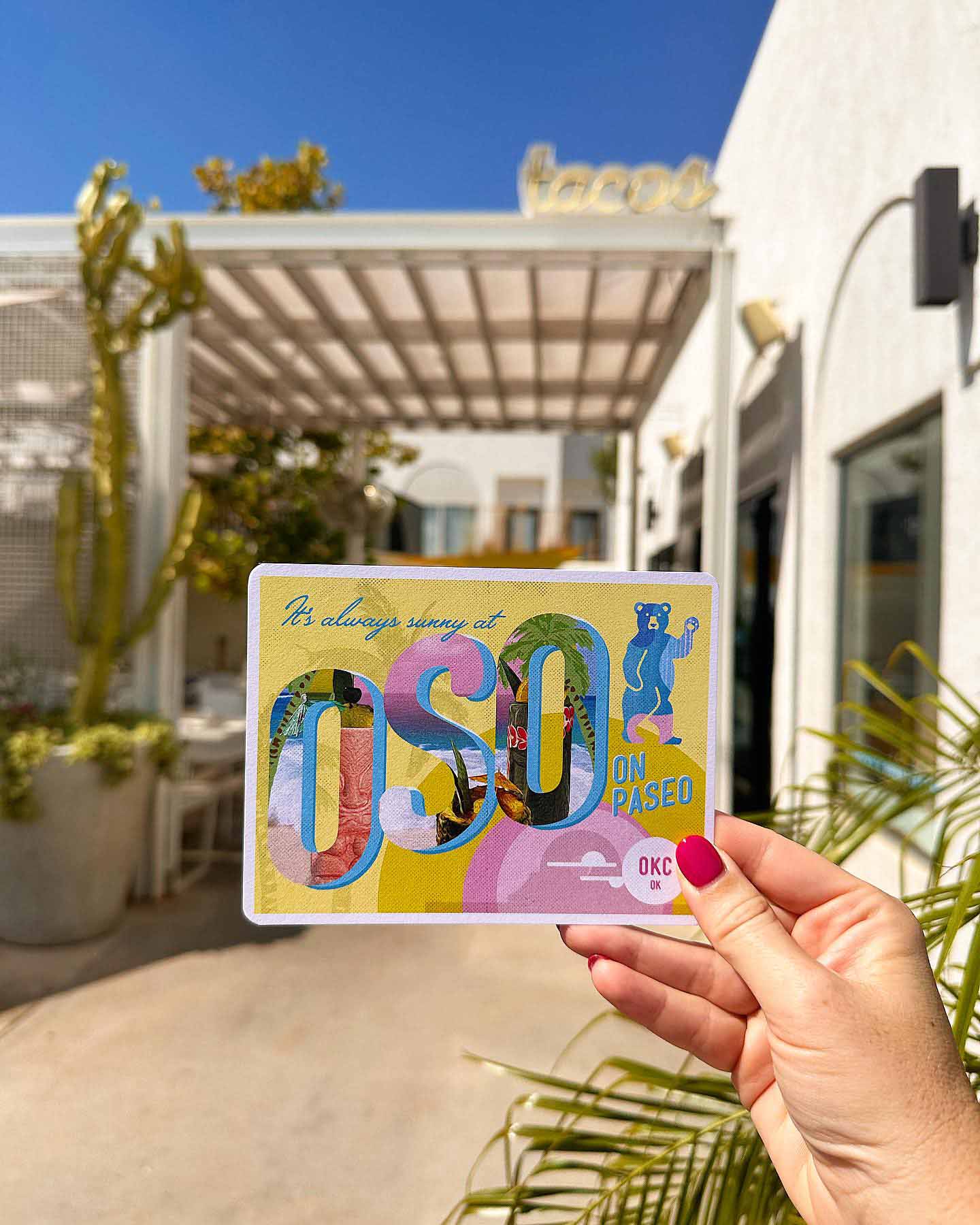 Woman's hand holding an OSO Paseo postcard outside of OSO Paseo's Restaurant in the Oklahoma Historic Paseo District.