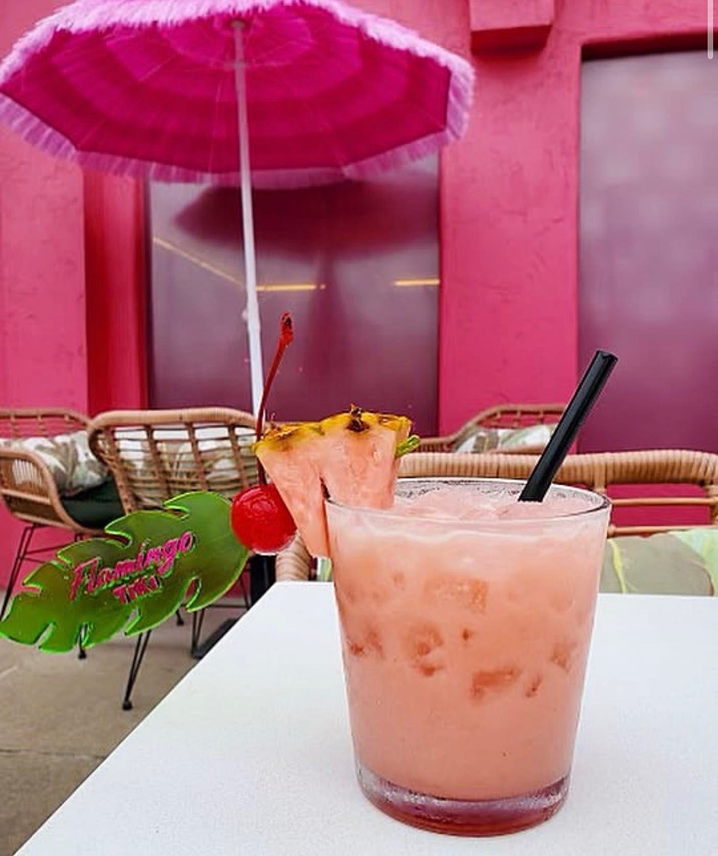 Flamingo Tiki Drink on the Patio with Pink Building and Umbrella in the background, located in the Oklahoma Historic Paseo District.